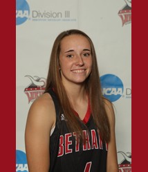 A Bethany Lutheran College basketball player in uniform smiles while posing in front of an NCAA Division III backdrop.