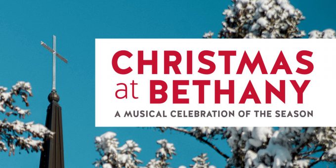 A snow-covered church steeple with a cross stands beside a sign that reads Christmas at Bethany, likely welcoming students and visitors to the holiday festivities at Bethany Lutheran College.