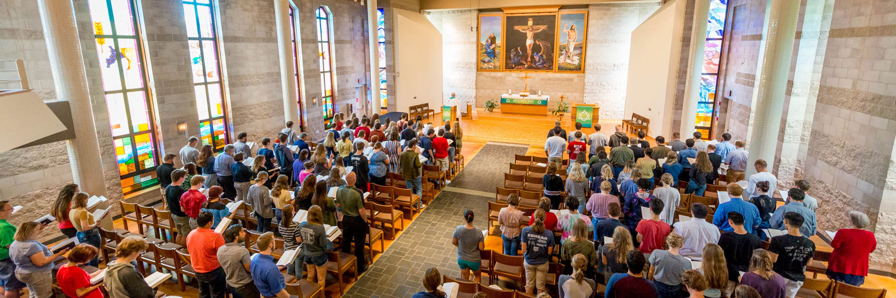 Students at Bethany Lutheran College in Minnesota attend a church service surrounded by stained glass windows and religious artwork.