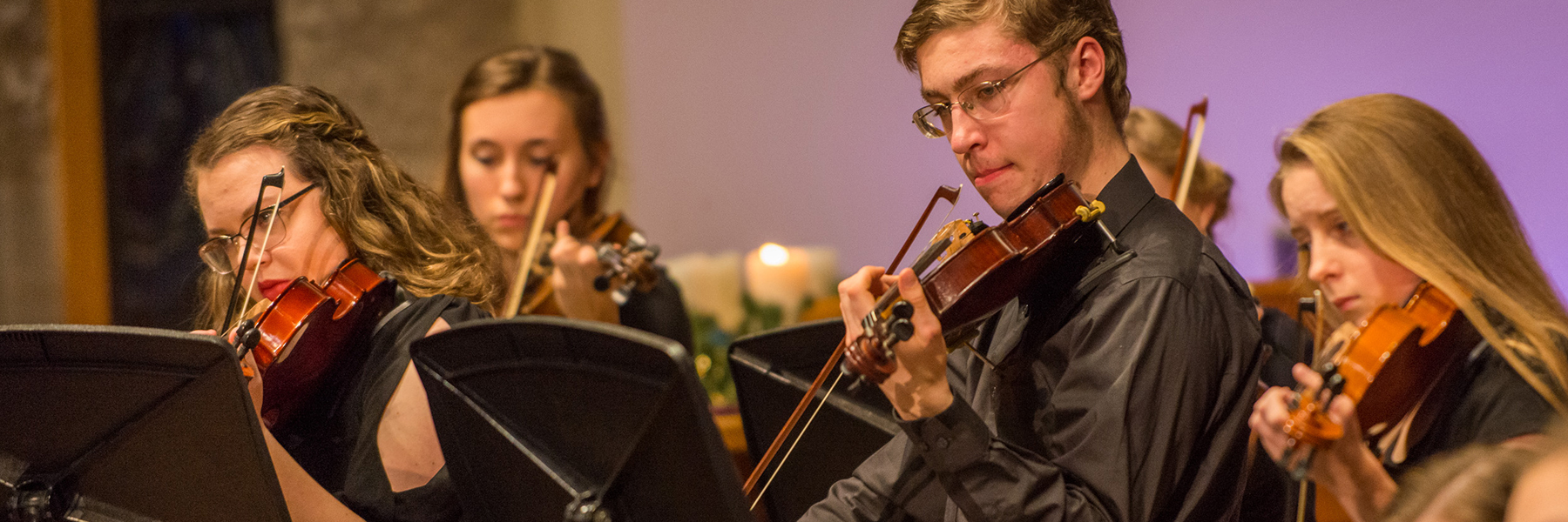 Four young violinists from Bethany Lutheran College perform together in concert, engaging students.