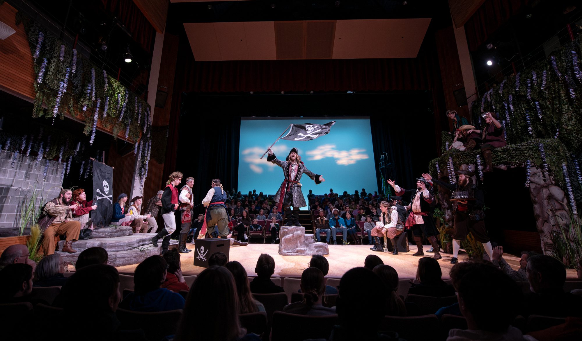 Actors perform a pirate-themed play on stage in Minnesota, engaging students in the audience.