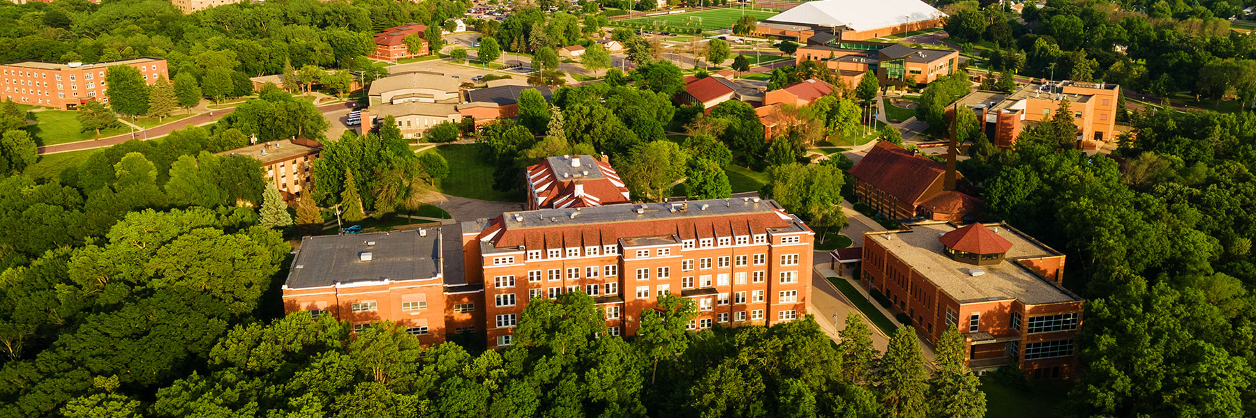 Aerial view of the Bethany Lutheran College campus community featuring red-brick buildings surrounded by trees and green spaces.