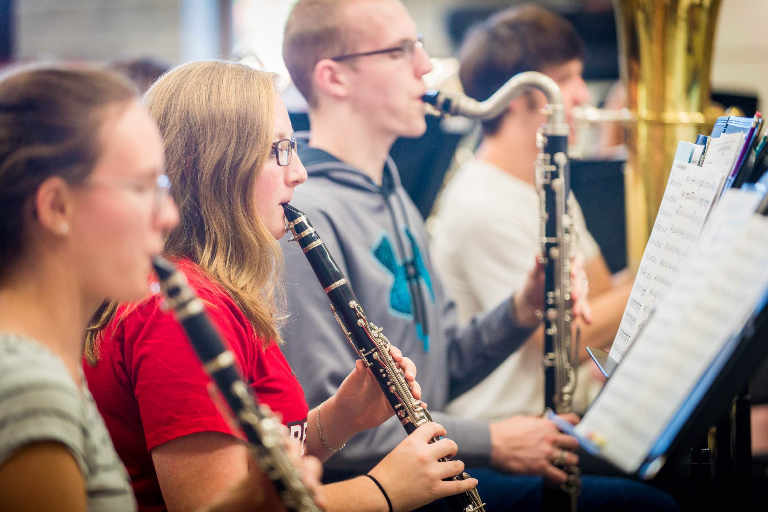 Four students in Minnesota play clarinets and other wind instruments while reading sheet music, promoting student engagement.