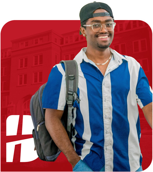 Smiling male college student wearing glasses, a backward cap, and a blue-and-white striped shirt, with a backpack over one shoulder, standing in front of a red background with a faded academic building and white "B" logo.