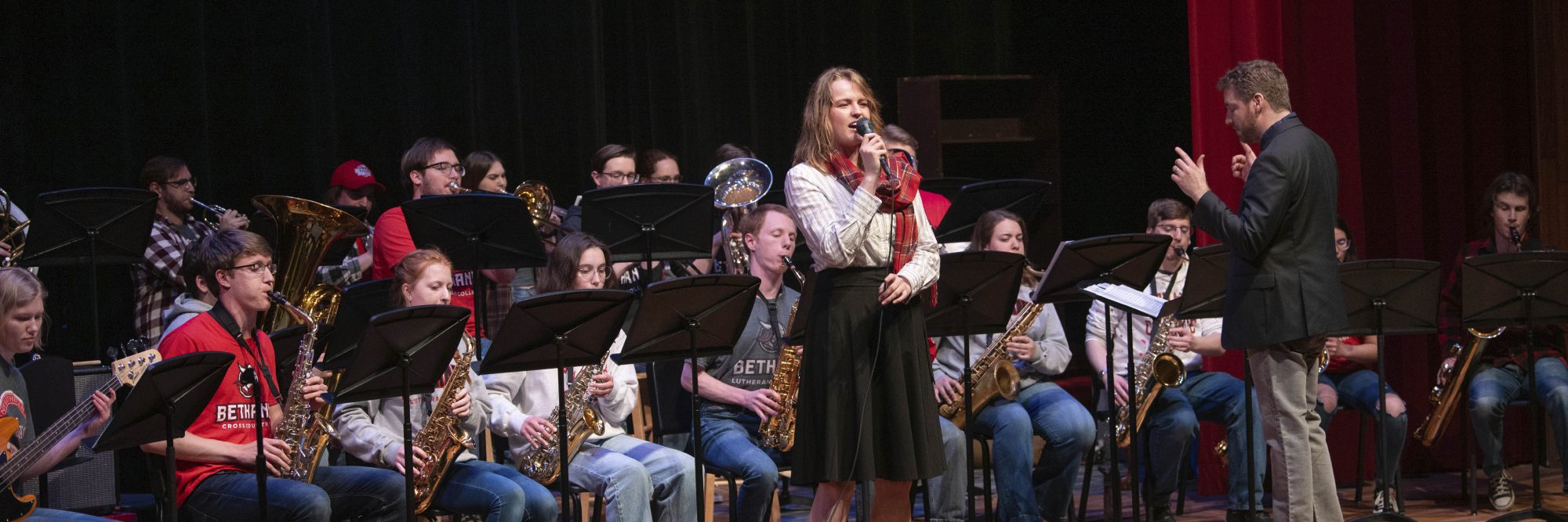 A band from Bethany Lutheran College in Mankato, Minnesota performs on stage, with a woman singing at the center.