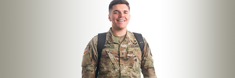 Bethany Lutheran College graduate Josh Grove in a U.S. Army uniform smiles while standing against a plain, light-colored background.