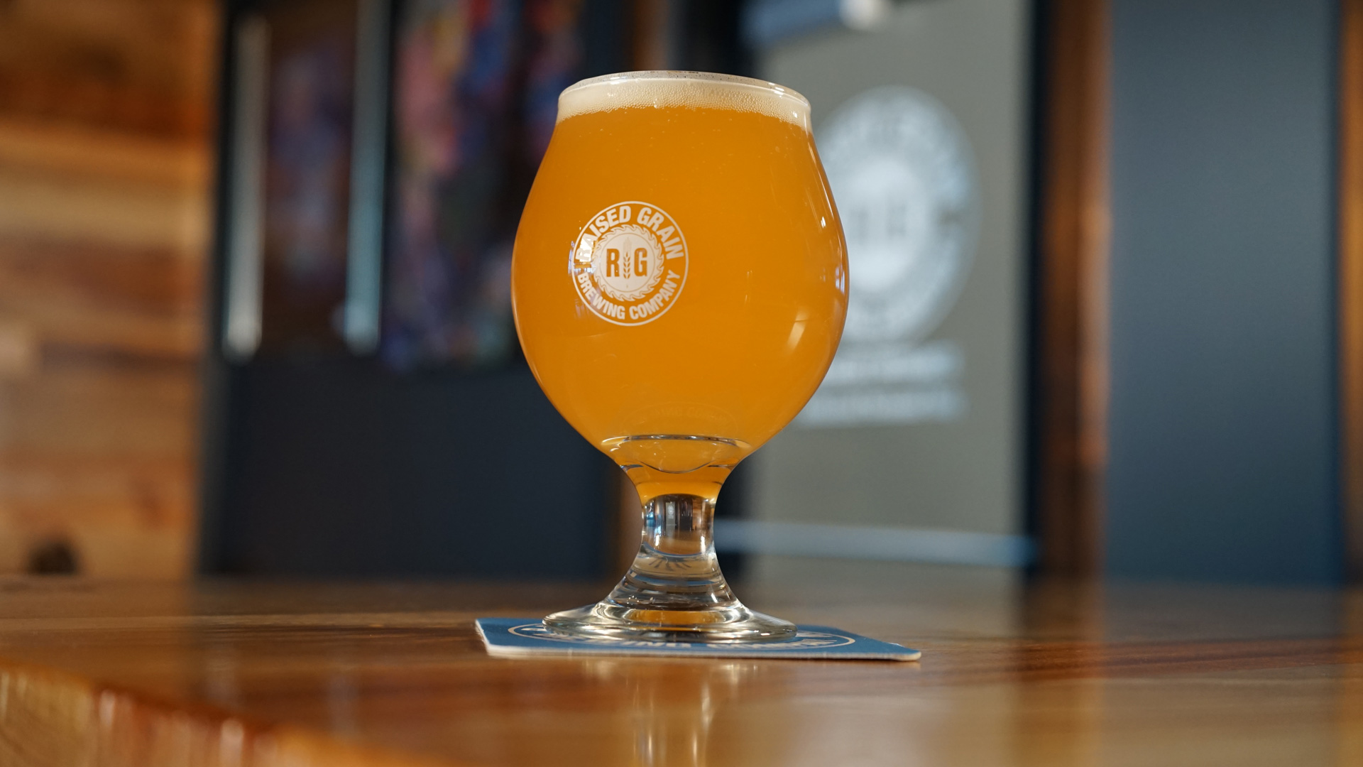 A tulip glass filled with hazy orange beer sits on a coaster atop a bar in Minnesota, offering a vibrant and inviting scene. This photo does not feature Bethany Lutheran College students or branding.