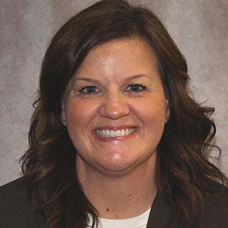 Shannon Reichel, Office Assistant for the Advancement Department, against a grey background.