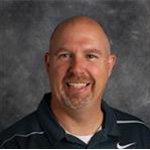 Andy Krueger, Associate Professor for the Business Administration Department, posed against a gray mottled background.