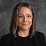 Angie Johnson, Associate Professor for the English Department and Writing Center Coordinator of the Academic Affairs Department, against a gray backdrop.