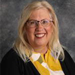 Ann Fredrickson, Adjunct Faculty, Choraliers Director, Director of Handbells, and Mary Martha Singers Director for Music Department, poses against a gray studio backdrop.