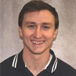 Ben Foss, Data & Messaging Coordinator for the Admissions Department, poses in front of a tan backdrop.