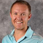 Ben Petzel, Senior Admissions Counselor for the Admissions Department poses in front of a gray backdrop at Bethany Lutheran College.
