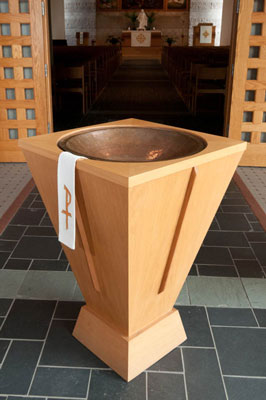 A wooden baptismal font covered with a white cloth in a the Bethany Lutheran College Chapel.