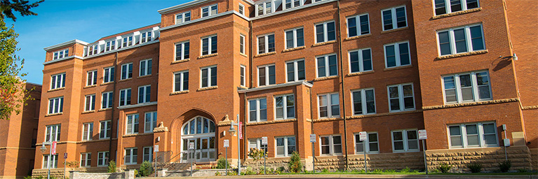 A large red-brick building with numerous windows and an arched entrance on the Bethany Lutheran College campus in Minnesota.