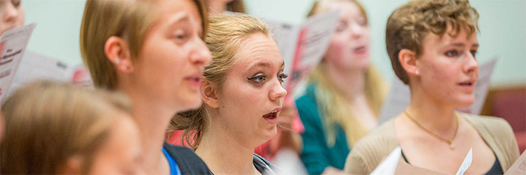 Students at Bethany Lutheran College hold sheet music and sing together during a lively choir rehearsal on campus.