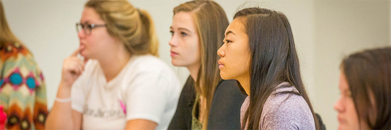 Four young women sit and listen attentively in a classroom, illustrating student engagement at Bethany Lutheran College.