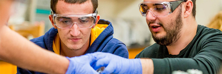 Two students at Bethany Lutheran College wear safety goggles and gloves, demonstrating engagement in a science lab.