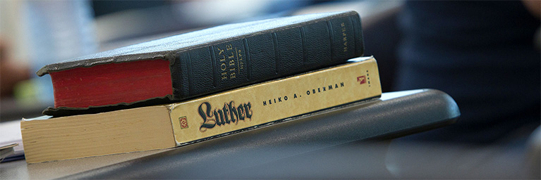 A Bible and a book titled Luther are stacked on a desk, indicating student engagement in a Mankato classroom.