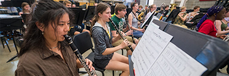 Students in Mankato play wind instruments in a classroom while reading sheet music, engaging actively in their lesson.