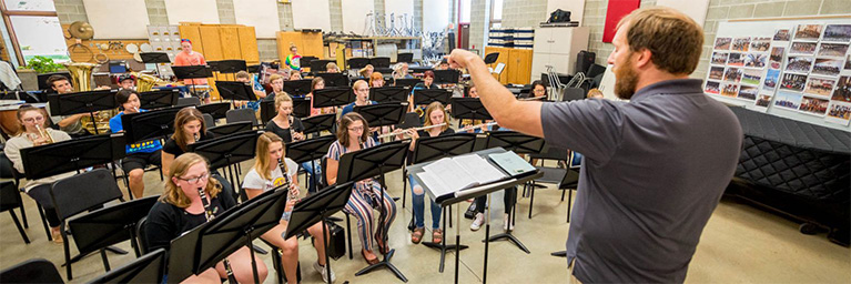 A band director leads students engaging in playing instruments together in a community classroom on the Mankato campus.