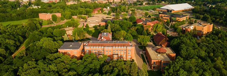 Aerial view of Bethany Lutheran College’s brick campus, surrounded by trees and additional buildings in lush Minnesota.