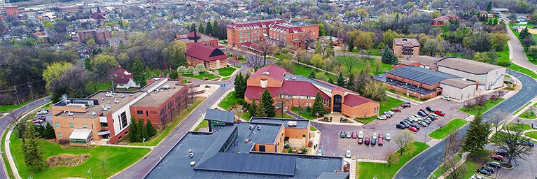 Aerial view of Bethany Lutheran College campus in suburban Minnesota, showing multiple buildings, parking lots, and surrounding trees.