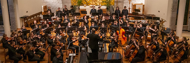 A conductor leads a large orchestra at Bethany Lutheran College in Mankato, Minnesota.