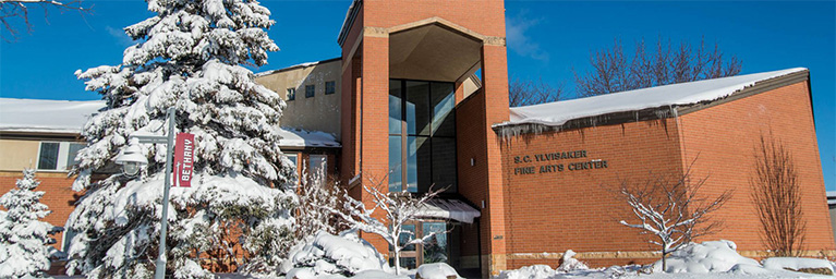 The Fine Arts Center at Bethany Lutheran College in Mankato is covered in snow, surrounded by snow-covered trees beneath a clear blue sky.