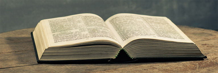 An open book sits on a wooden surface at Bethany Lutheran College in Minnesota, with a dark, blurred background.