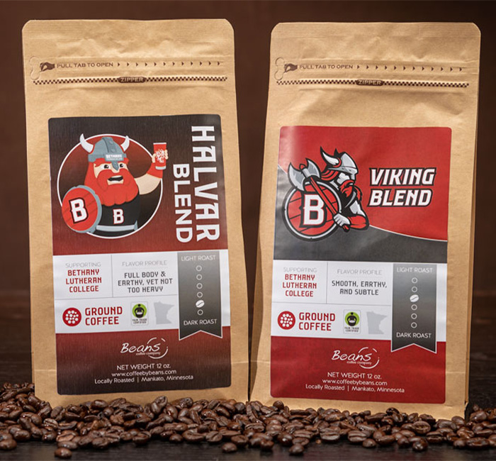 Two coffee bags—Halvar Blend and Viking Blend—are displayed upright with coffee beans scattered around them. Ideal for Bethany Lutheran College students in Mankato seeking fresh, local brews.