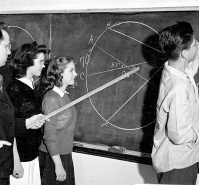 Four students at Bethany Lutheran College stand by a chalkboard filled with geometric diagrams, with one student actively pointing at the board.
