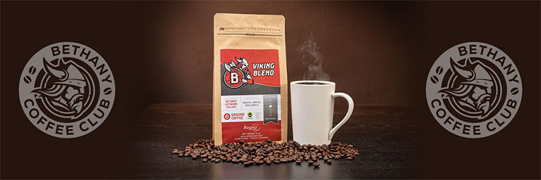 A bag of Viking Blend coffee and a mug are placed on a table with coffee beans, featuring the campus community and Bethany Coffee Club logos.