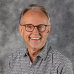 Craig Ferkenstad, Adjunct Faculty for the Religion Department, standing in front of a gray mottled background.