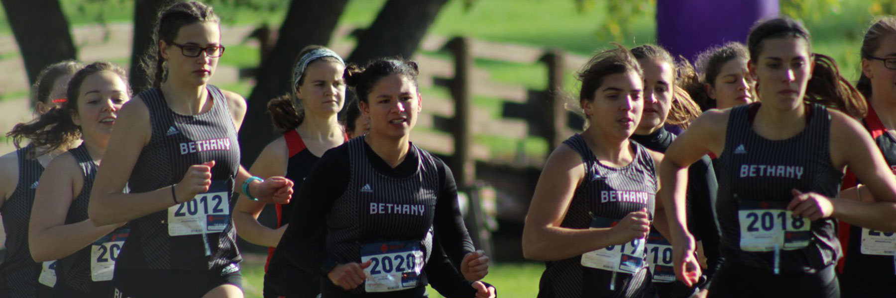 A group of female runners wearing Bethany uniforms compete in a cross-country race on the Minnesota campus.