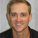 Danny Kneeland, Assistant Coach Baseball and Facilities Support for the Athletics Department, against gray background.