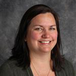 Darci Theiste, Payroll and Account Specialist for the Business Office Department, poses in front of a mottled gray background.