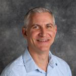 David Norris, Director of Visual Communication for the Institutional Communication Department, against a gray backdrop.