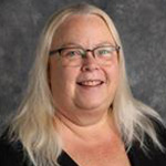 Deborah Matzke-Lewis, Director of the Nursing Department, standing in front of a gray background at Bethany Lutheran College.
