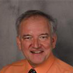 Dennis Marzolf, Adjunct Faculty of the Music Department, posed in front of a gray backdrop.