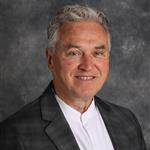 Don Moldstad, Director of Campus Spiritual Life for the Spiritual Life Department, poses in front of a gray background.
