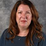 Elizabeth Olson, Associate Professor for the Business Administration Department and Taylor Leadership Institute for the Academic Affairs Department, posed in front of a gray mottled background.