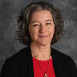 Jenna Thompson, Fine Arts Center Event Coordinator for the Academic Affairs Department, poses in front of a gray background.