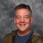 Jon Geistfeld, Accounts Payable Clerk for the Business Office Department, in front of a gray mottled background.