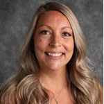 Katie Hopp, Visual Communication & Social Media Specialist for the Institutional Communication Department, posed in front of a mottled gray background.