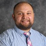 Lucas Fricke, Associate Professor for the Languages Department and Director of the E-Sports Department, against grey background.