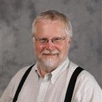 Mark Degarmeaux, Professor for the Religion Department, against a gray background.
