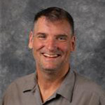 Mike Fletcher, Superintendent of Buildings Technician for the Maintenance Department, against grey background.