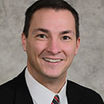 Patrick Garvin, Head Men's Basketball Coach and Co Athletic Director, poses in front of a gray background.