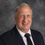 Robert Hanna, Professor for the English Department, standing against gray background.